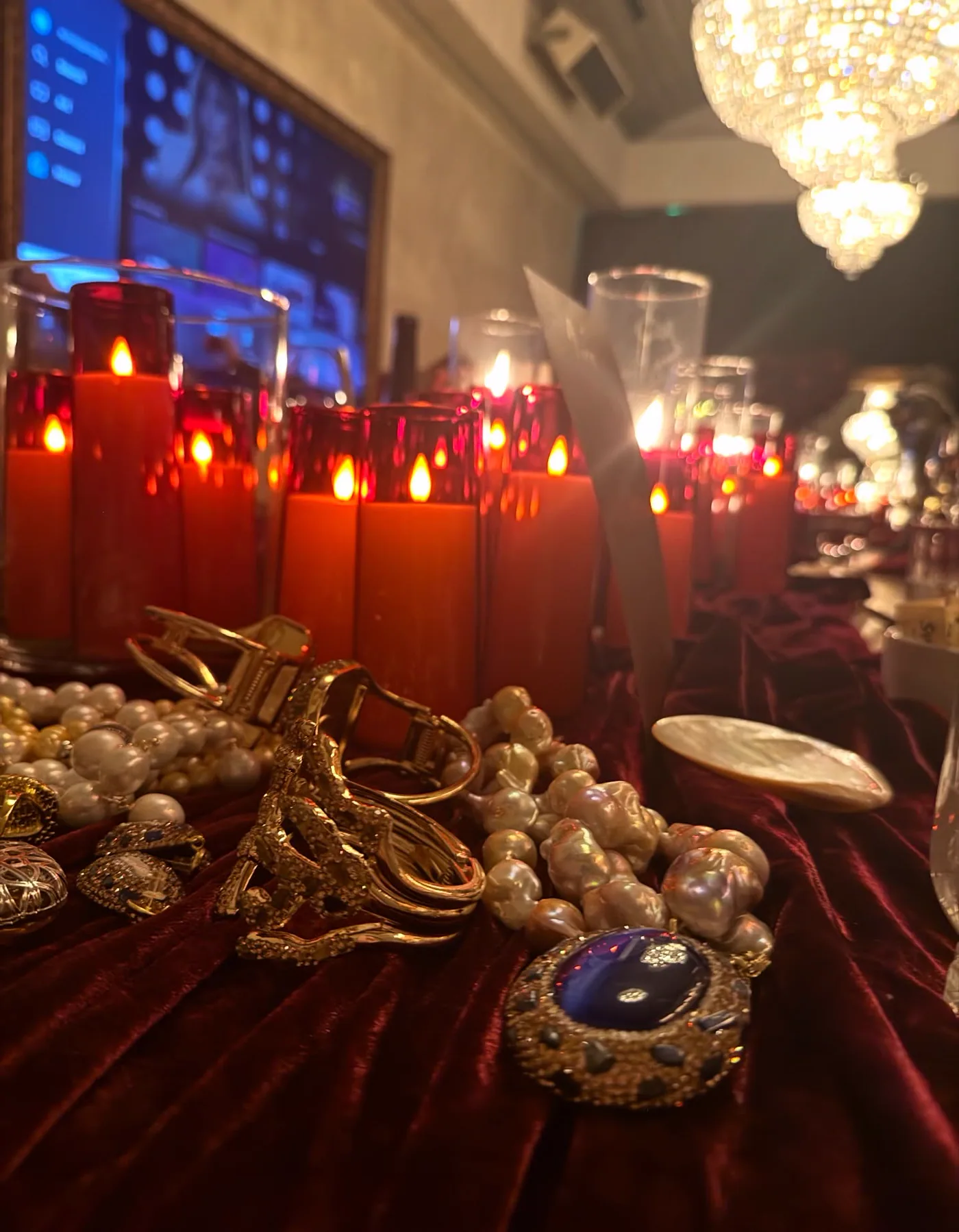 Pearls and gold jewellery on velvet between red candles