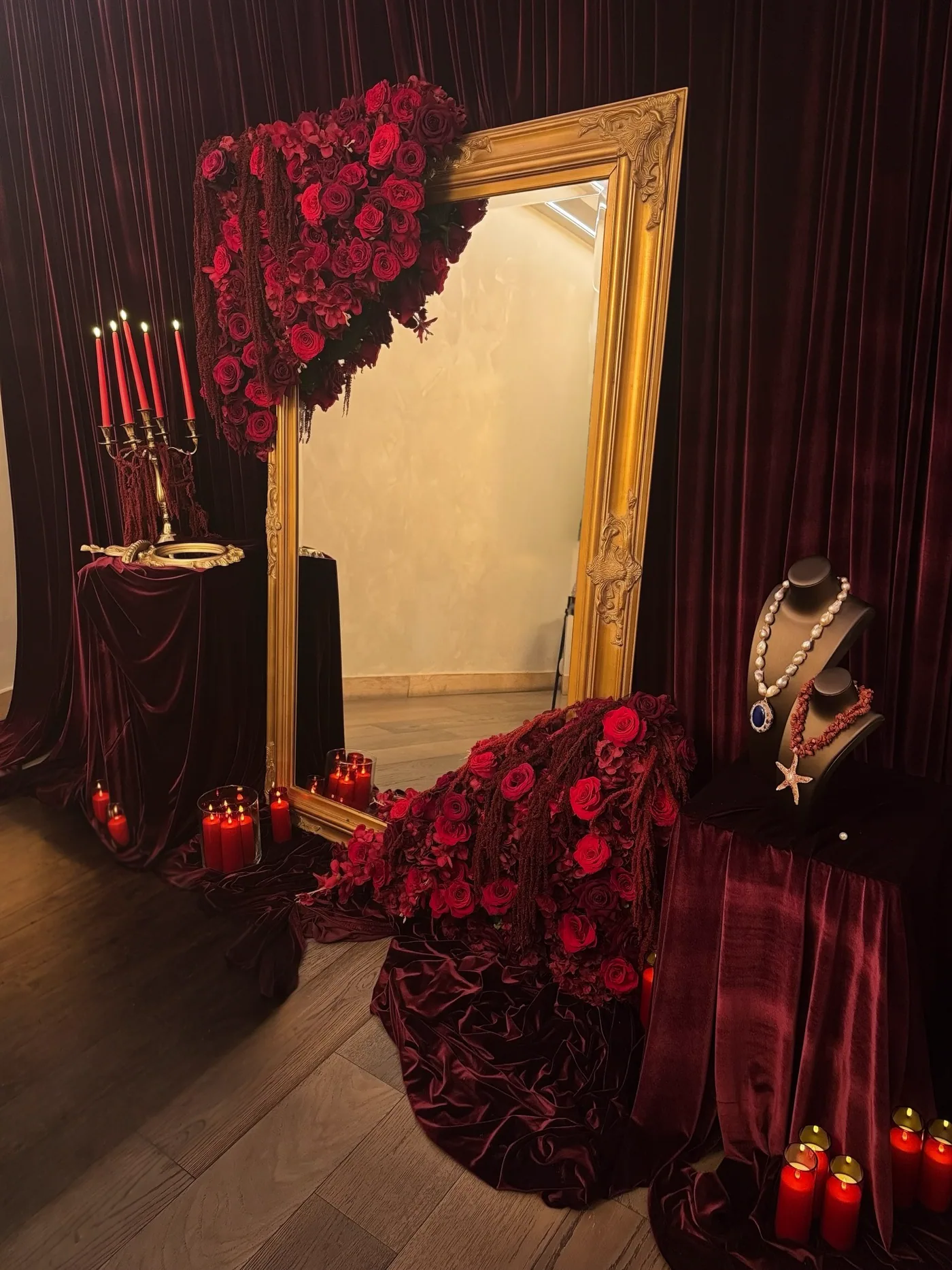 A gilded mirror framed with red roses and burgundy velvet
